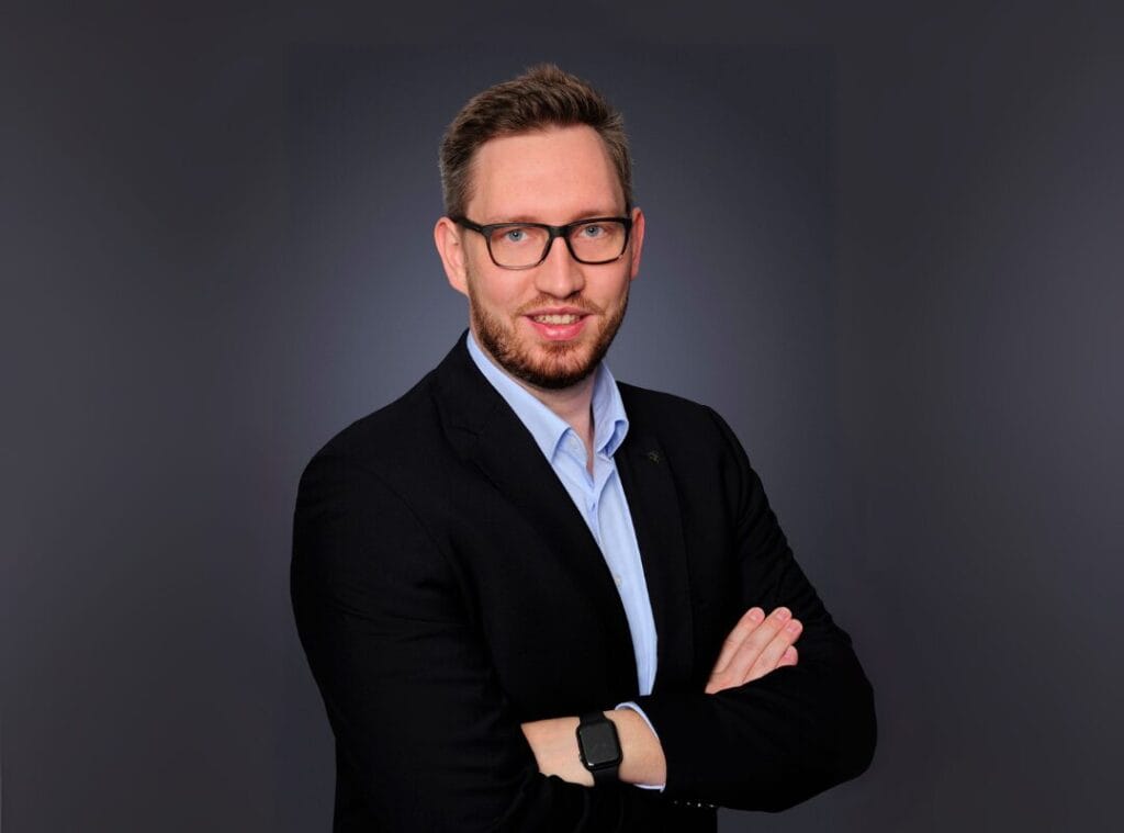 Mann im Anzug mit Brille und verschränkten Armen