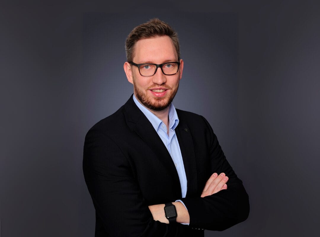 Mann im Anzug mit Brille und verschränkten Armen